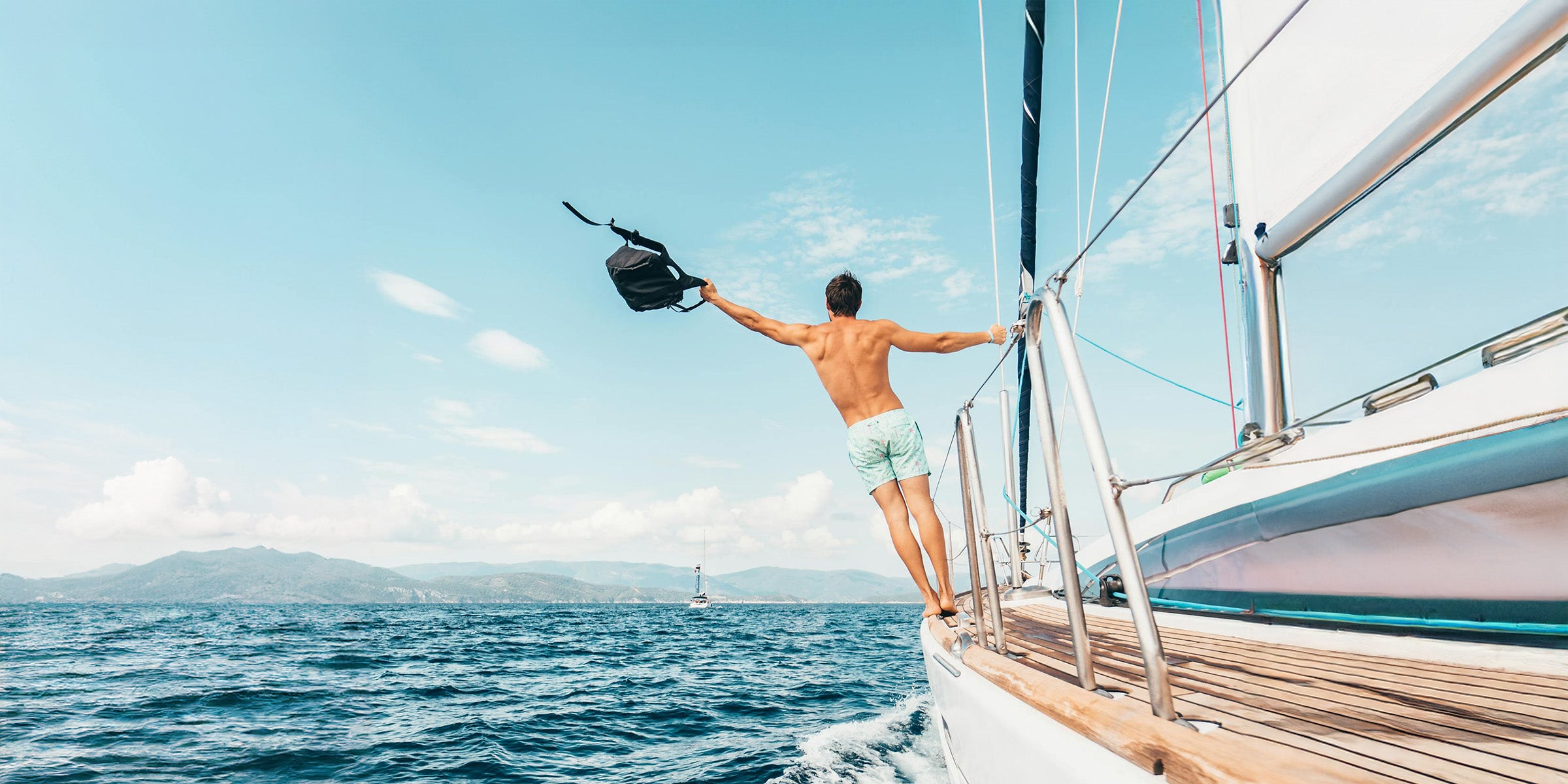 Man hanging off boat with Airopack backpack